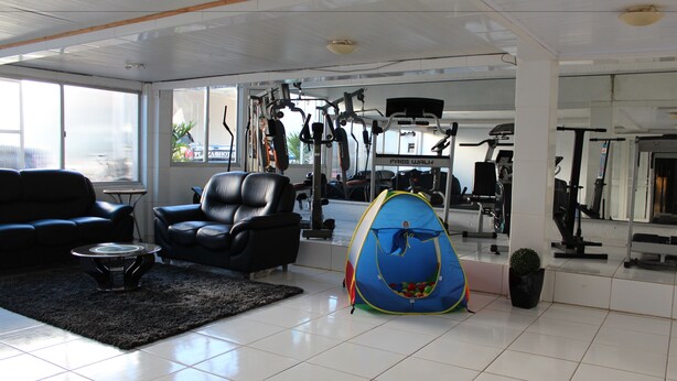 A spacious living area with a black leather sofa, a small coffee table, and a blue play tent. - Lages Plaza Hotel (Lages)