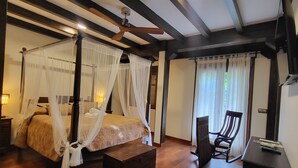 Ein Schlafzimmer mit einem Himmelbett, einem Schreibtisch und einem Sessel.