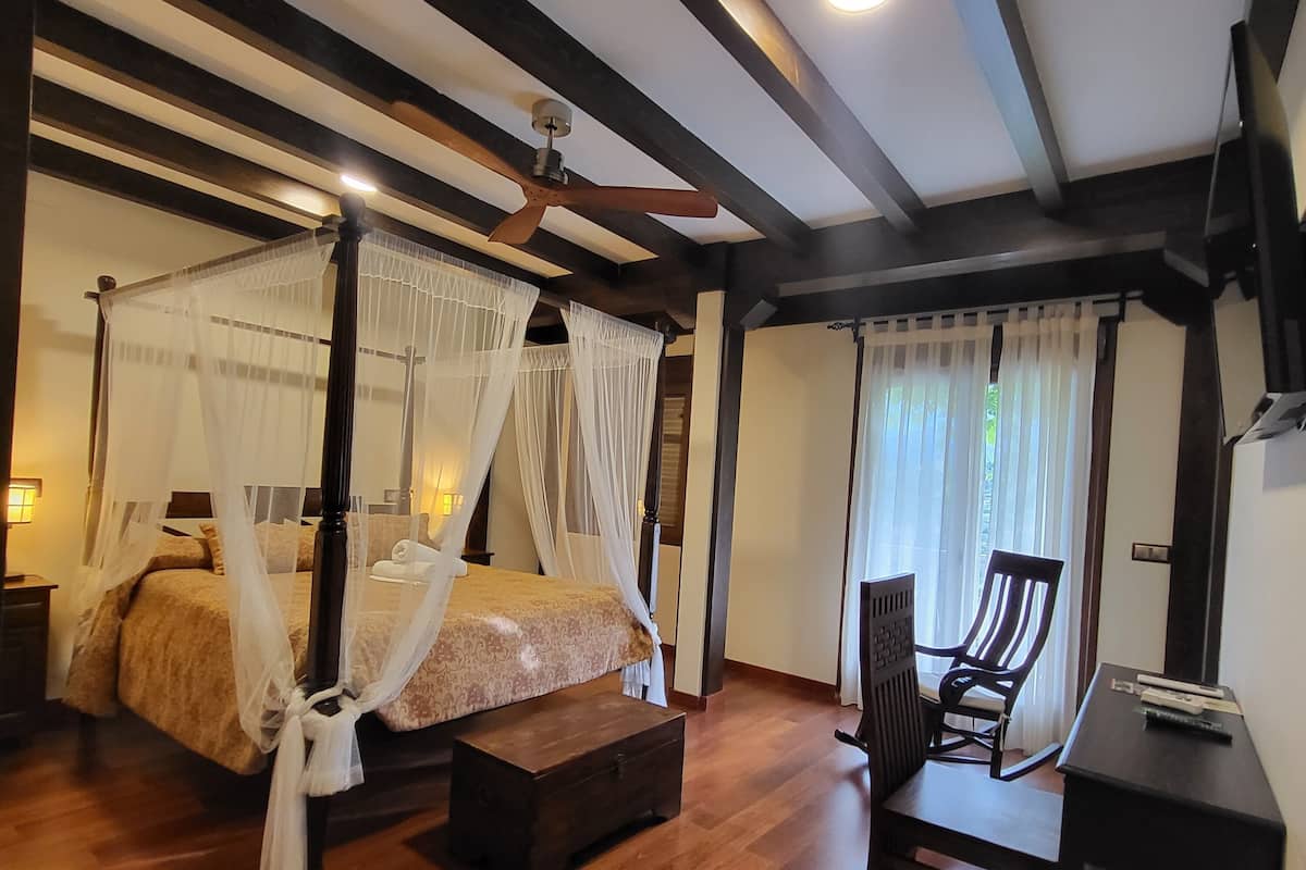 Quarto com cama de dossel, escrivaninha e cadeira.