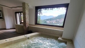 Ein Whirlpool mit Blick auf eine gebirgige Landschaft durch ein Fenster.