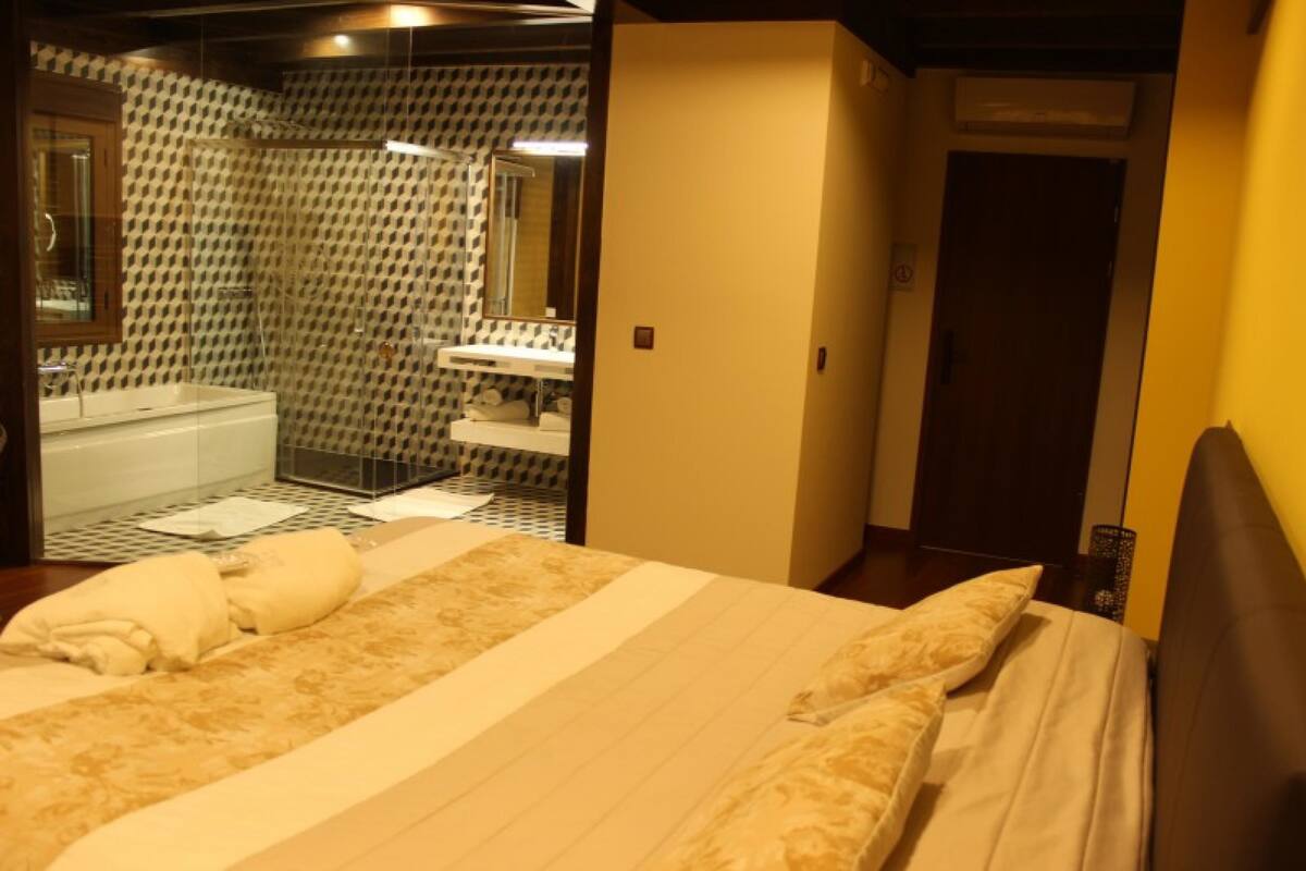 Quarto de hotel com uma cama, banheiro com chuveiro e porta que dá para outro quarto.