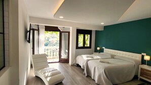 Ein Schlafzimmer mit zwei Betten, einem Sessel, einem Fernseher und einem Balkon mit Vorhängen.