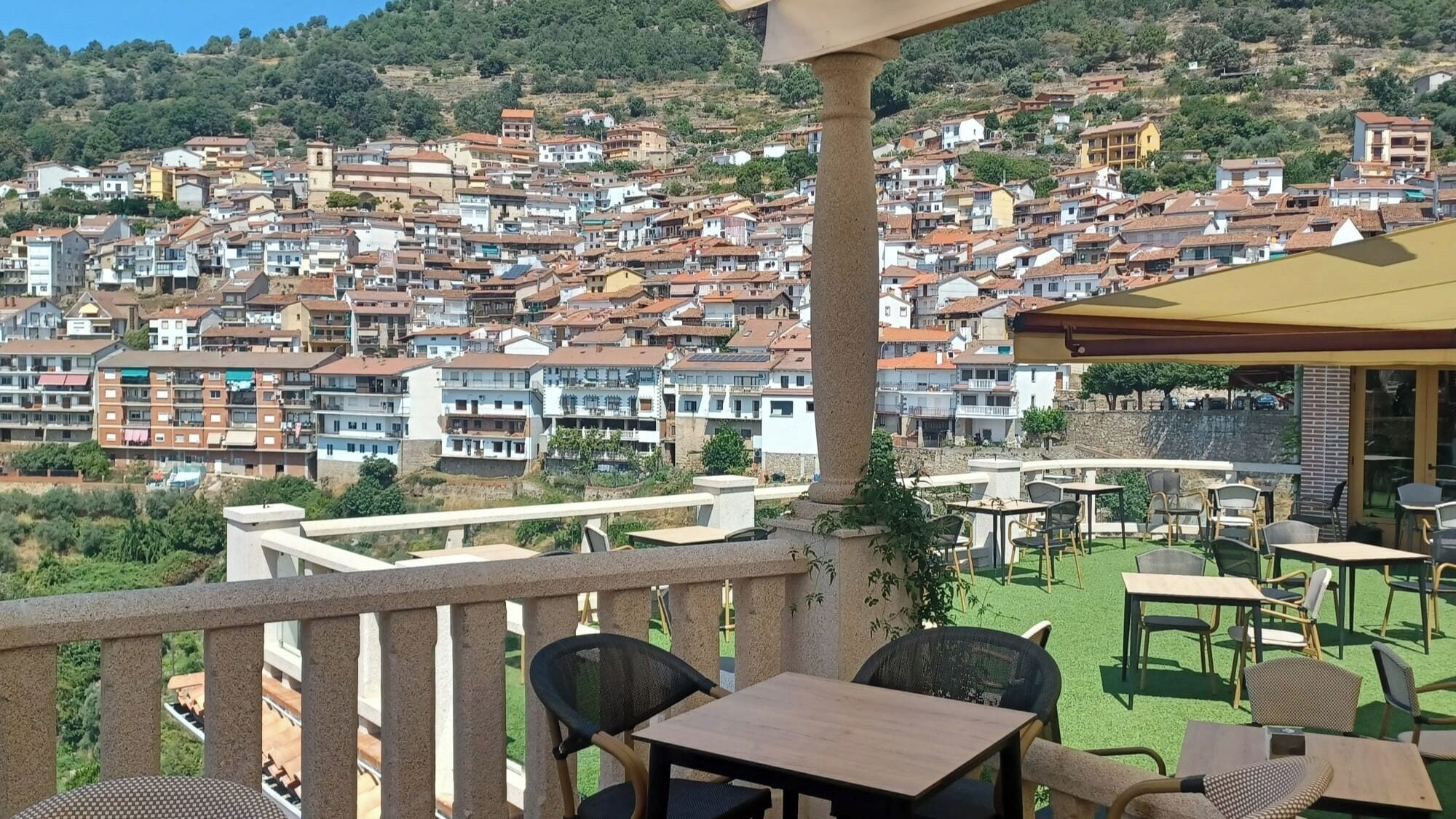A terrace with outdoor seating, overlooking a densely packed hillside residential area.