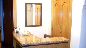 A kitchen with a granite countertop, wooden cabinets, and a mirror on the wall.