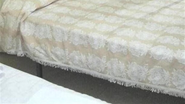 A bedroom with a bed, a wooden wardrobe, and a curtain.