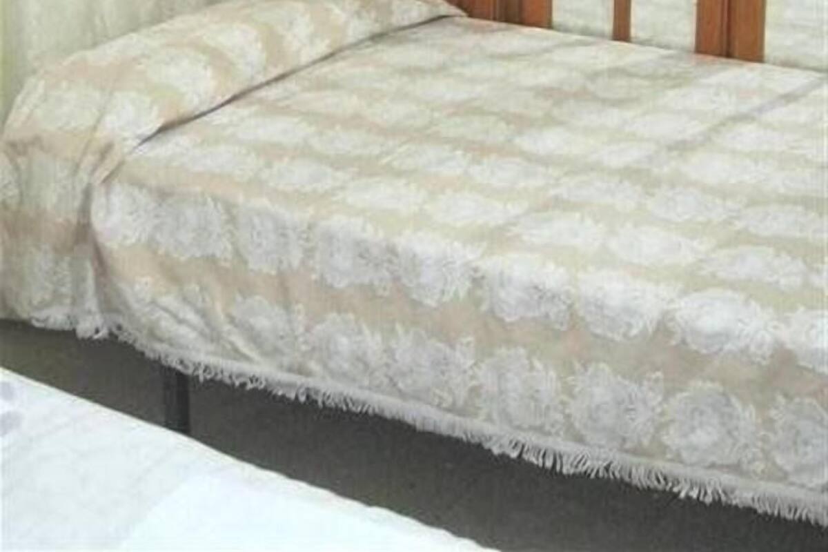 A bedroom with a bed, a wooden wardrobe, and a curtain.