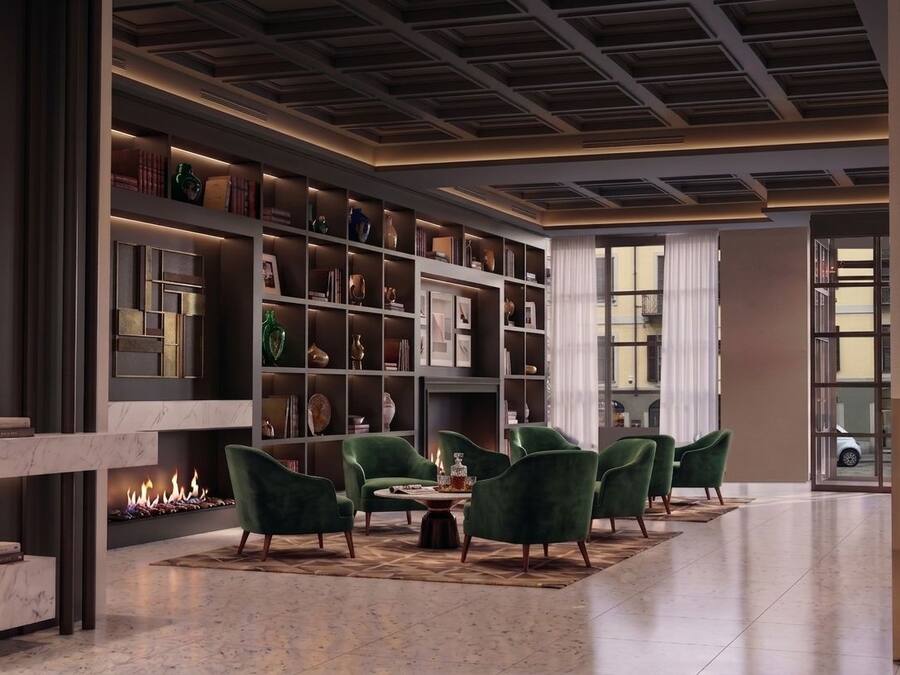 Un interno moderno con camino, poltrone verdi e libreria.