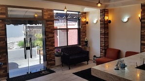 A modern living room with a sofa, armchairs, a coffee table, and a view through a glass door. - Hotel Buriti Itupeva (Itupeva)
