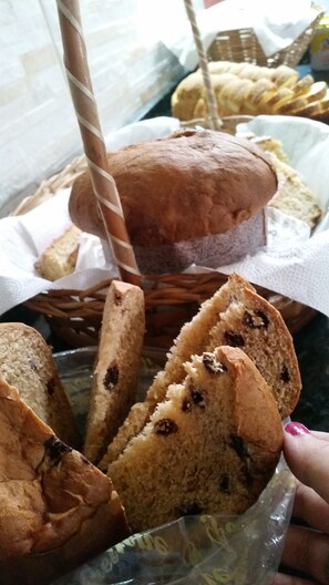 A basket of bread, including a loaf and sliced pieces, with a striped straw. - Hotel Buriti Itupeva (Itupeva)