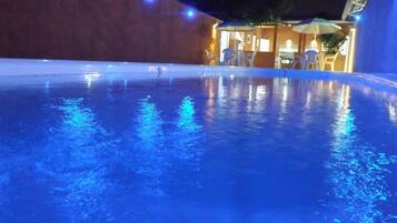 Alberca al aire libre, sombrillas en la alberca y camastros