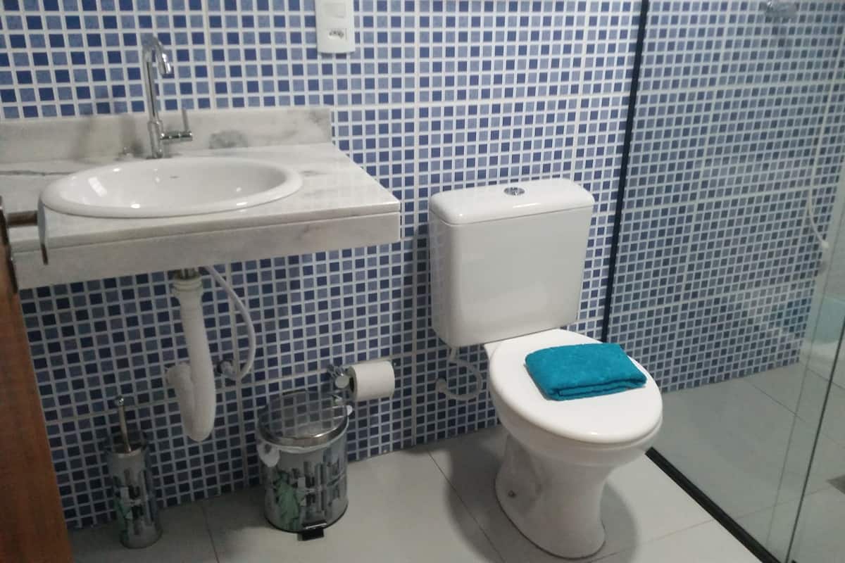 A bathroom with a white sink, a toilet with a blue towel, and blue-tiled walls.
