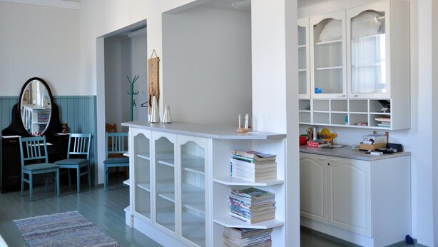A room with a piano, chairs, a white cabinet with glass doors, and a bookshelf. - Opintola Bed & Breakfast (Teuva)