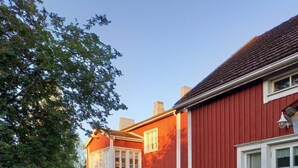 A red building with white trim, a bench, and a pathway surrounded by greenery. - Opintola Bed & Breakfast (Teuva)