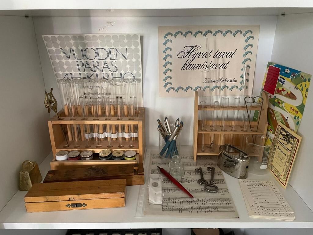 Exposició d'objectes antics, incloent vidrieria, utensilis metàl·lics i una caixa de fusta amb un pany.