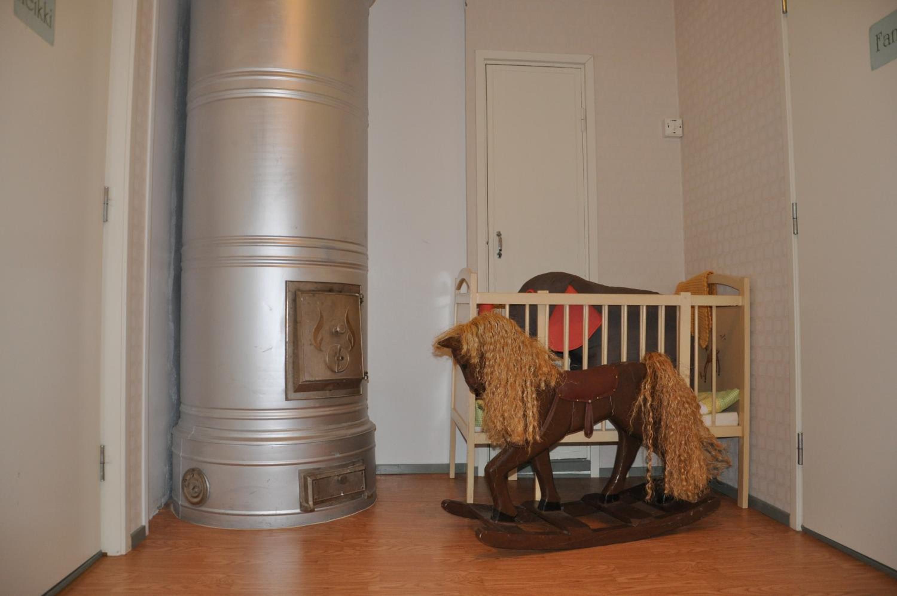 Een kamer met een groot, metalen cilindrisch object, een houten schommelpaard en een witte deur.