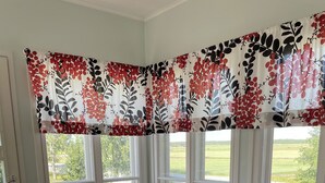 A living room with a brown sofa, a wooden coffee table, and a floral curtain. - Opintola Bed & Breakfast (Teuva)