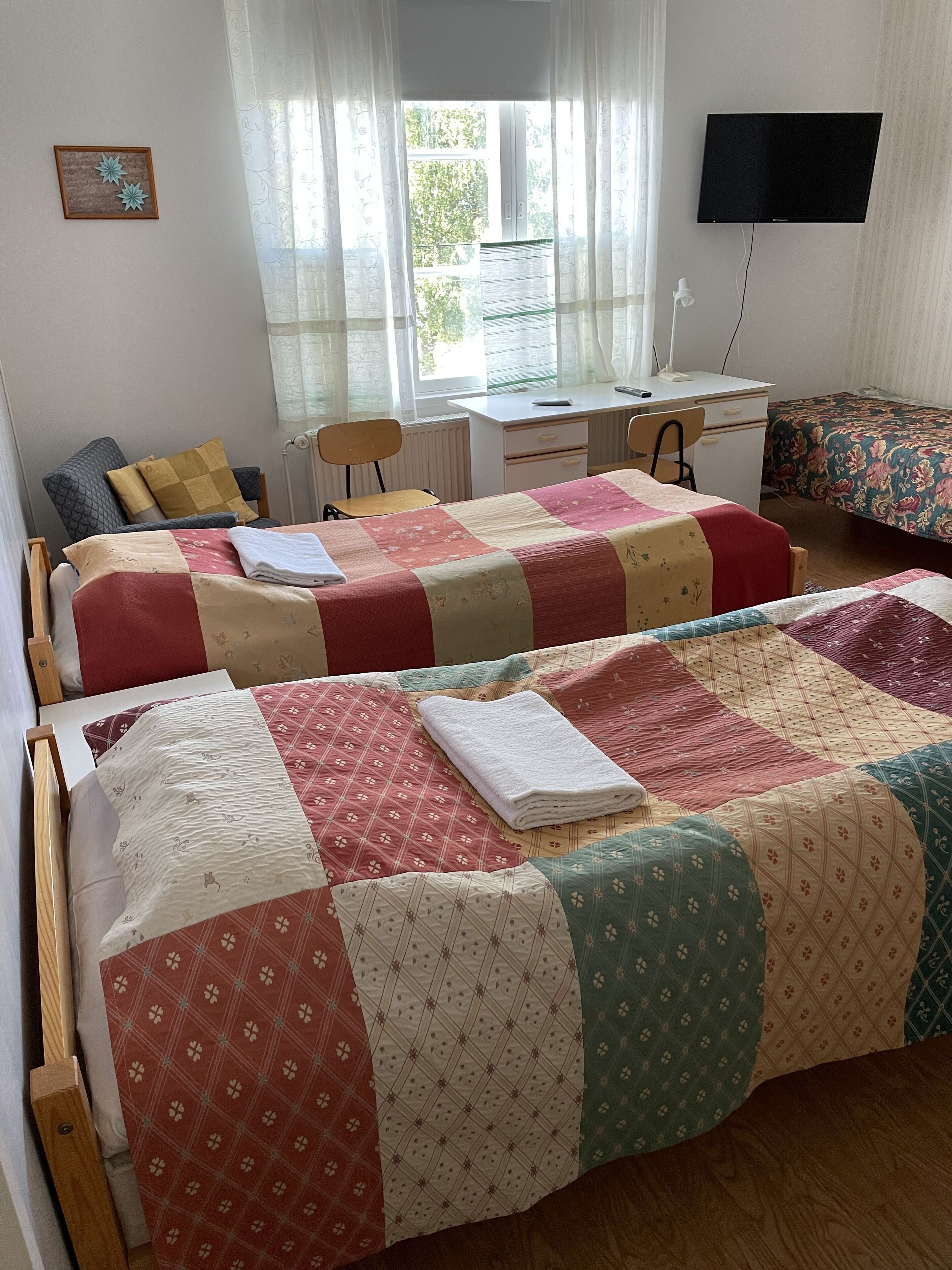 Een slaapkamer met twee bedden, een bureau en een televisie.