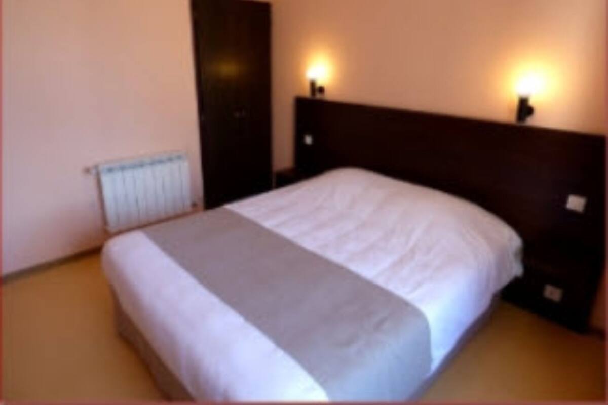 Een slaapkamer met een bed, twee bedlampen, een radiator en een deur.