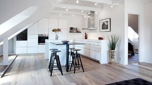A modern kitchen with white cabinetry, a central island, and bar stools. - WOW Apartments, Sankt Sigfridsgatan 64-66 (Gothenburg)