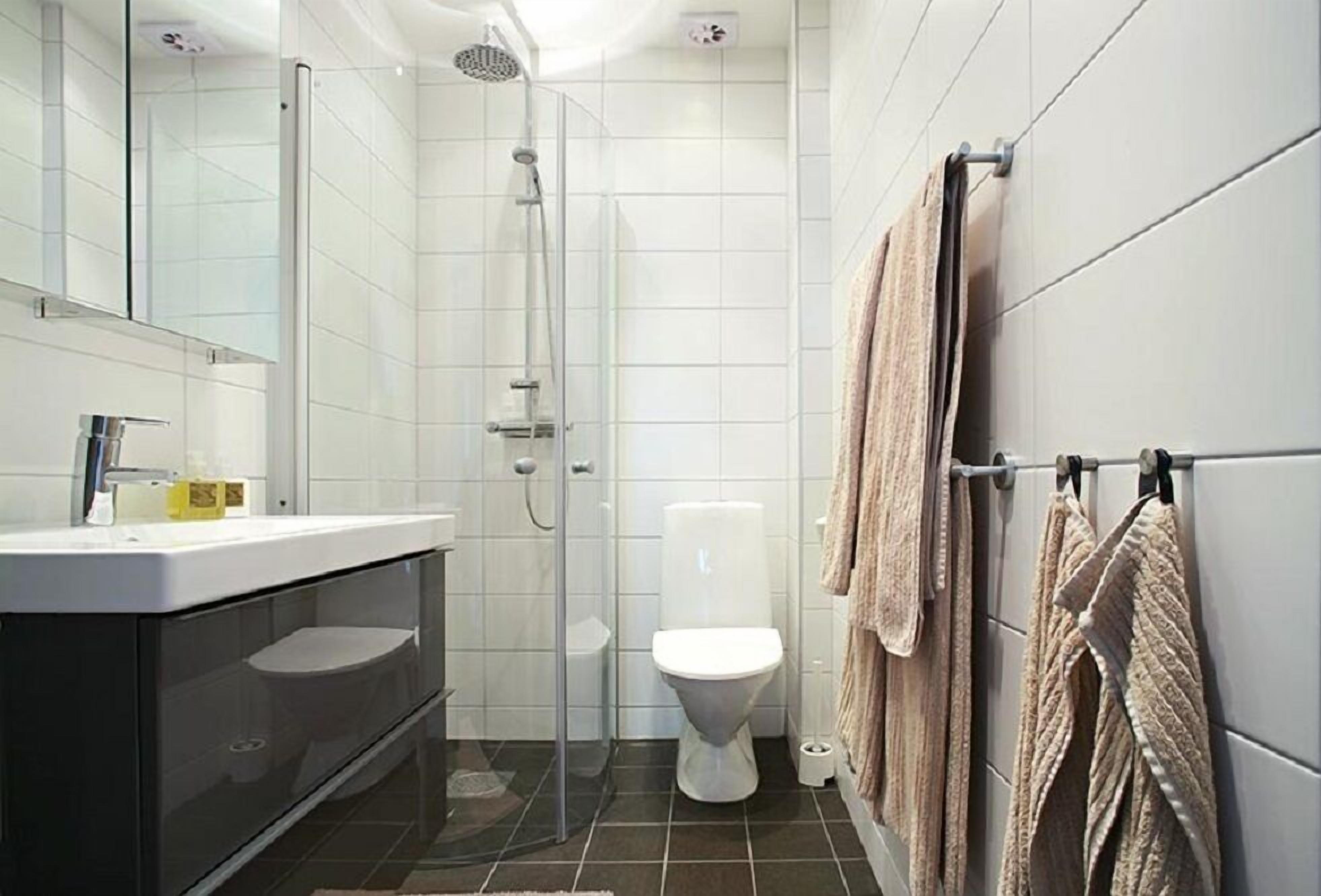 A modern bathroom with a glass-enclosed shower, a white toilet, and a black vanity with a mirror.