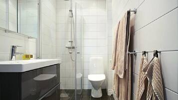 A modern bathroom with a glass-enclosed shower, a white toilet, and a black vanity with a mirror.