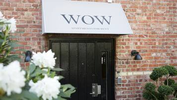 A brick building with a black door and a sign above it that reads "WOW APARTMENTS FOR RENT".