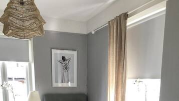 A bedroom with a bed, bedside table, lamp, desk, chair, and a window with curtains.
