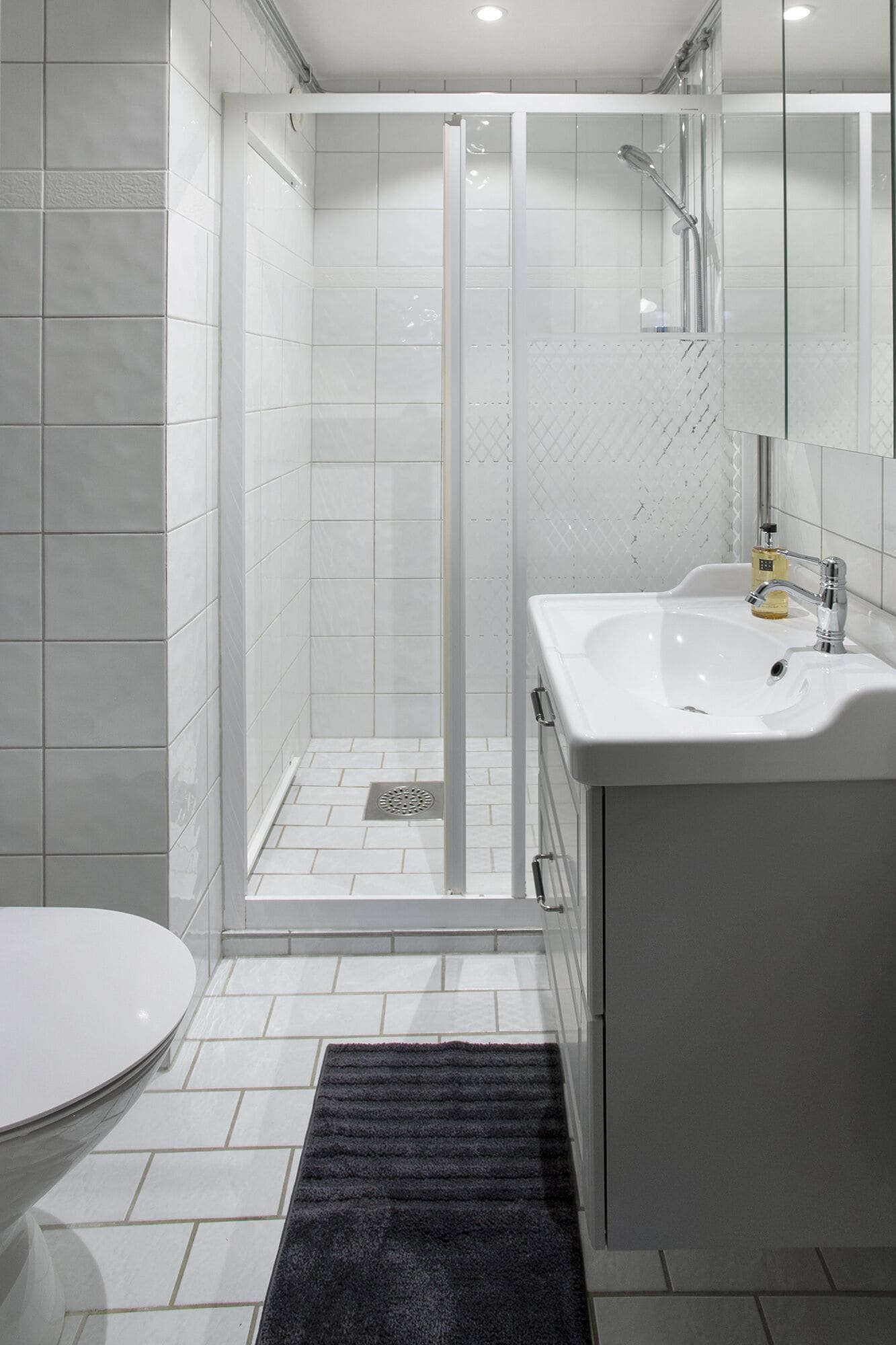 Een moderne badkamer met douche, toilet en wastafel.