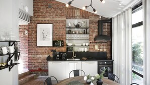 A kitchen with a brick wall, black appliances, and a dining area with a wooden table and chairs. - WOW Apartments & Rooms (Gothenburg)
