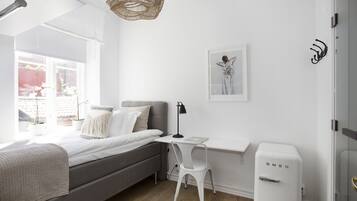 A modern bedroom with a bed, desk, chair, and a white radiator.