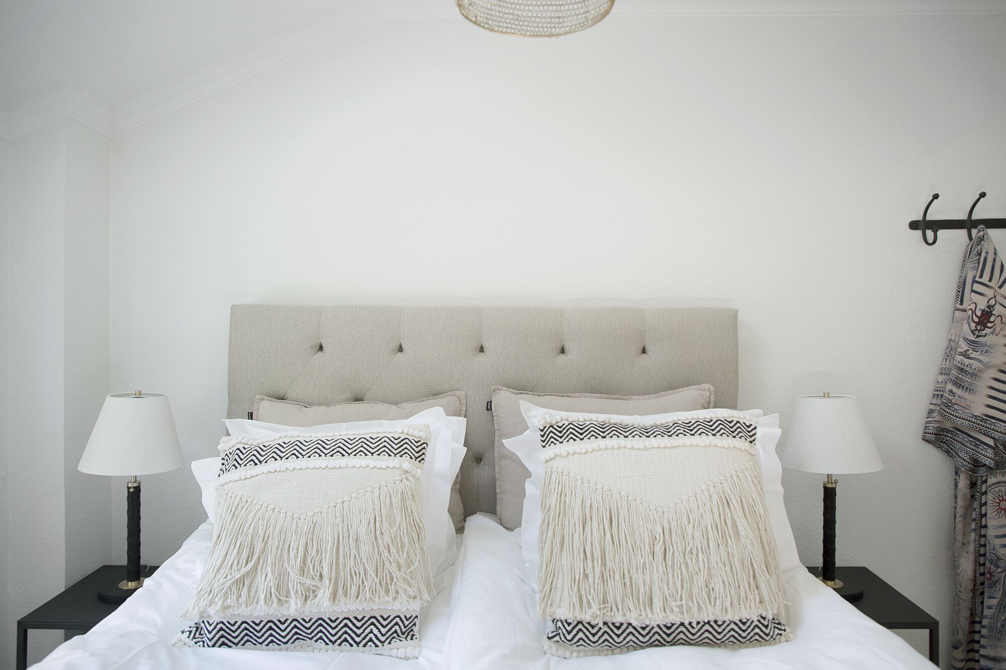 A neatly made bed with a tufted headboard, two bedside tables with lamps, and a patterned throw blanket.