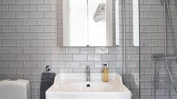 A modern bathroom with a white sink, two drawers, a mirror, and a shower.
