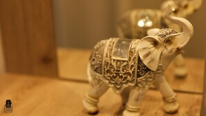 Una detallada figurina de elefante con diseños intrincados, sobre una superficie de madera.