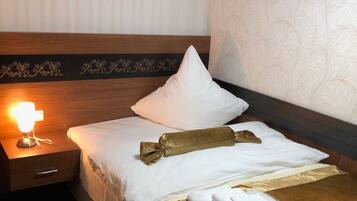 A hotel room with a bed, a nightstand, and a wall with a textured pattern.