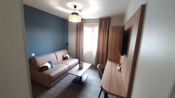 Une chambre moderne avec un canapé, une petite table, une chaise, un luminaire au plafond et une armoire.
