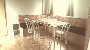 A dining area with a wooden table set for four, surrounded by white chairs. - Camping des Platanes (Charny-Oree-de-Puisaye)