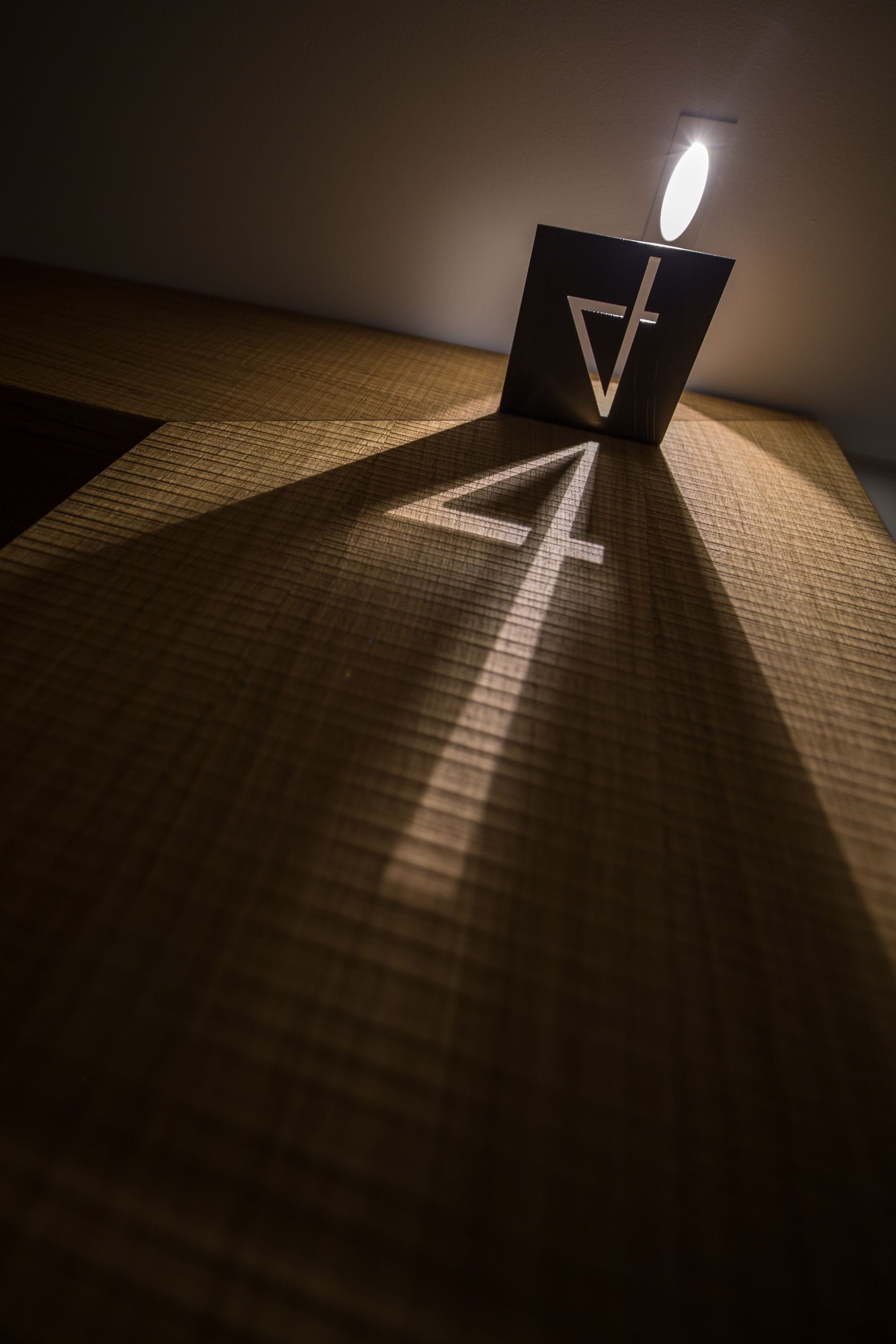 Una habitación con alfombra estampada y una lámpara de mesa proyectando una sombra.