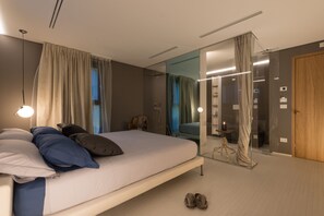 Une chambre moderne avec un grand lit, une cloison en verre et une porte en bois.