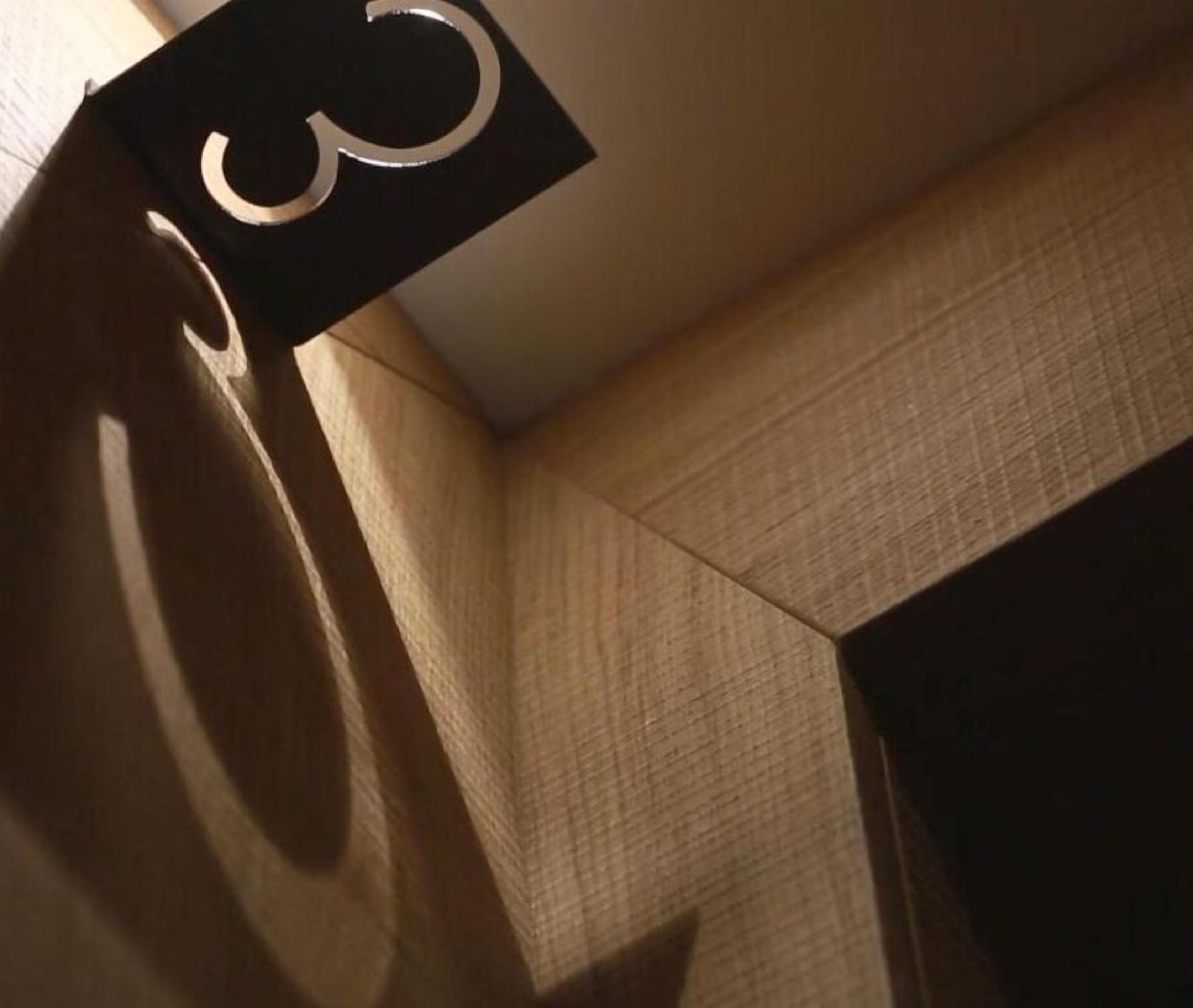 Een hoek van een kamer met een structuurwand en een zwart bord met een wit symbool.