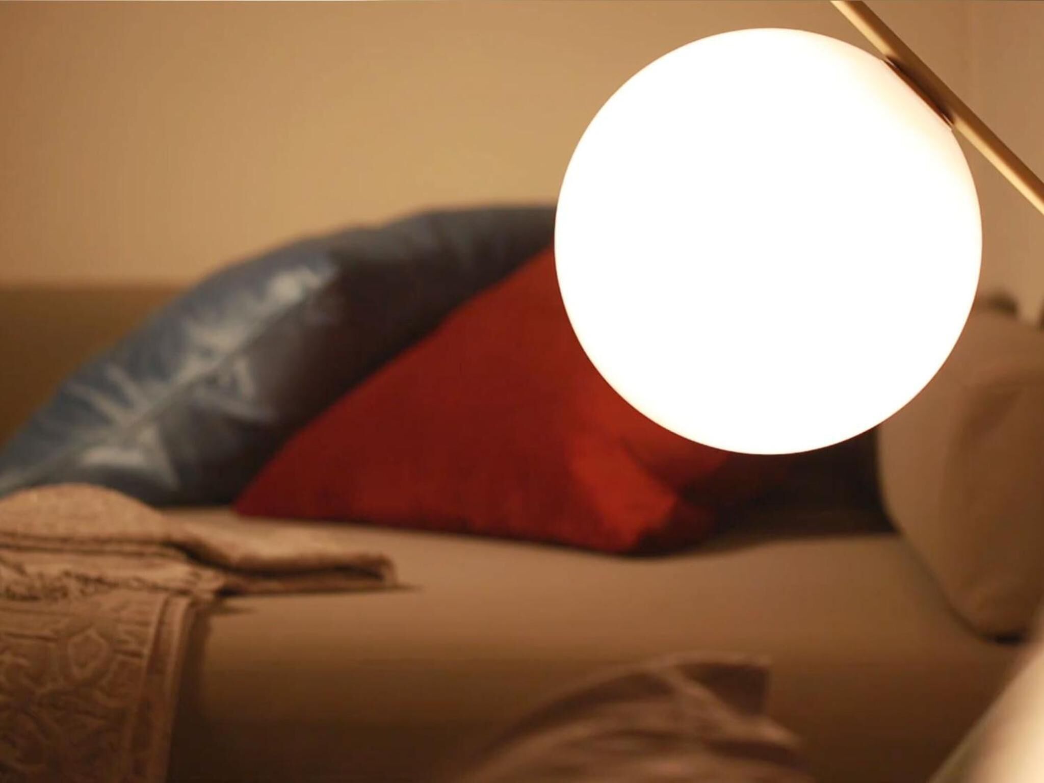 A room with a bed, pillows, and a lamp.