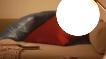 A room with a bed, pillows, and a lamp.