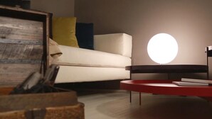 Una sala de estar moderna con un sofá blanco, una mesa de centro redonda roja y una lámpara de techo circular original.