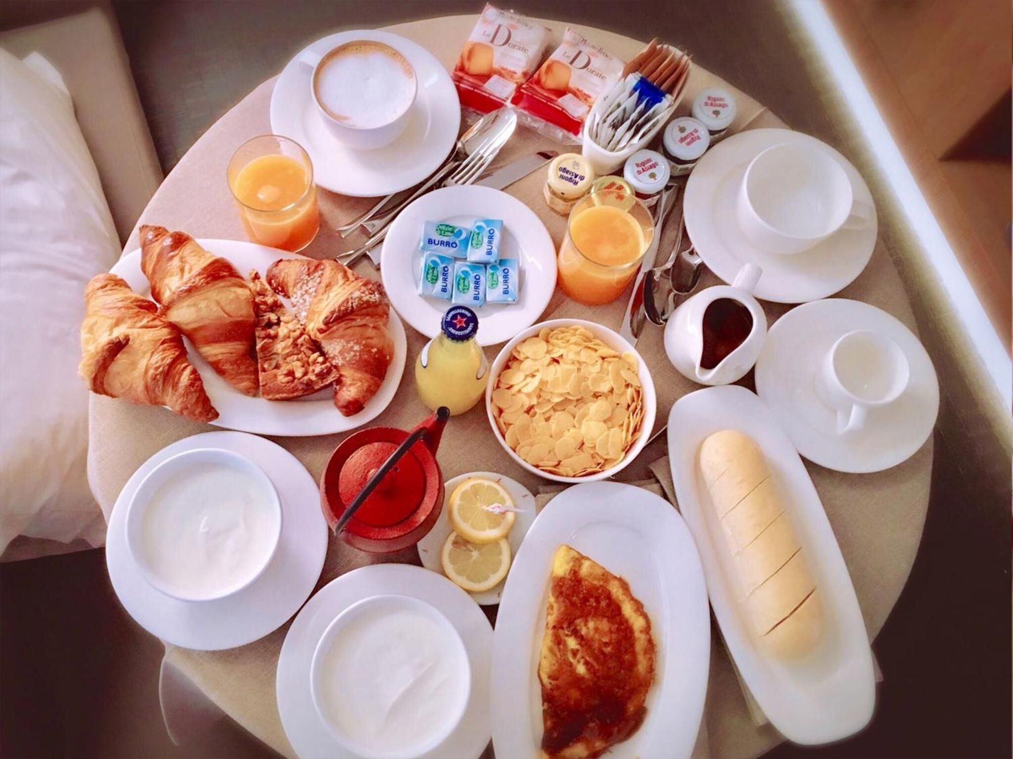Un plateau de petit-déjeuner avec des croissants, du jus, du café et divers condiments.