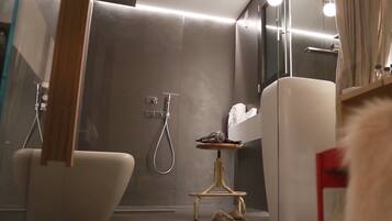 A modern bathroom with a glass shower enclosure, a white bathtub, and a small vanity with a mirror.