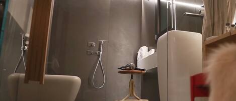 A modern bathroom with a glass shower enclosure, a white bathtub, and a small vanity with a mirror.