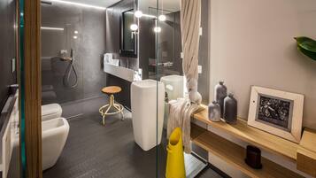 Un baño moderno con cabina de ducha de vidrio, inodoro blanco, tocador con espejo y estante con objetos decorativos.