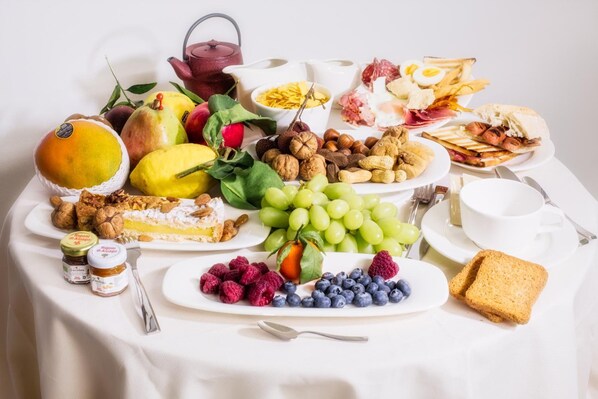 Un bufé de desayuno con frutas, nueces, quesos y pan.