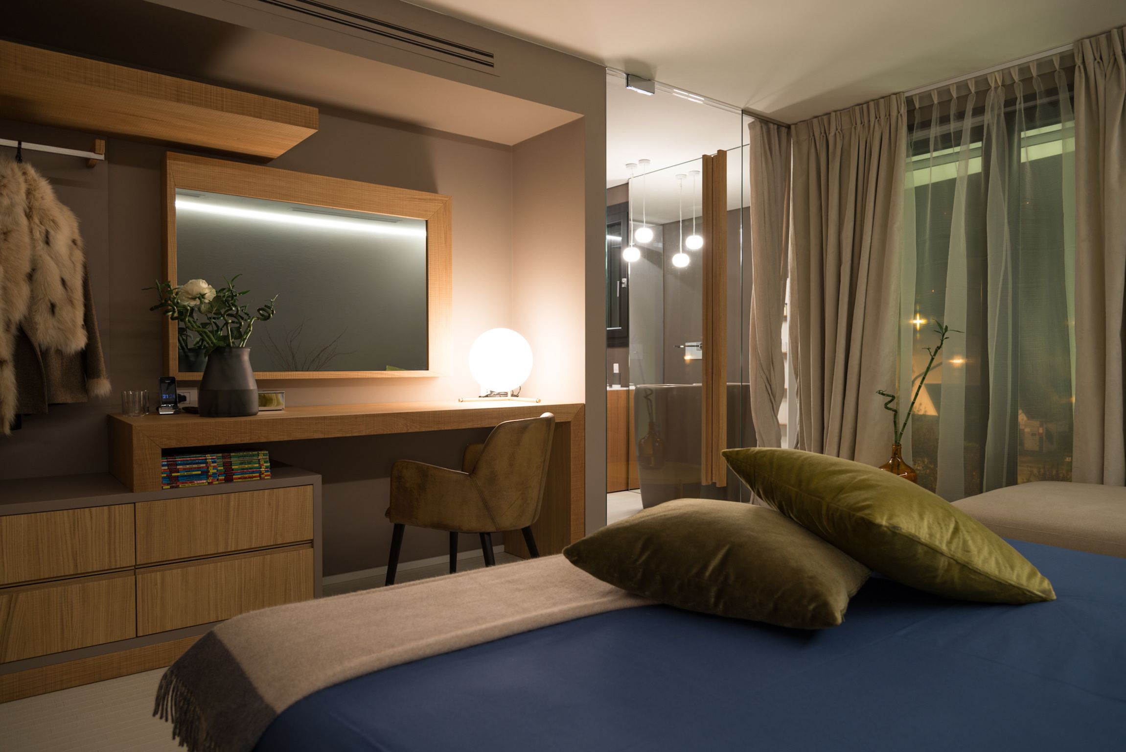 Et moderne hotelværelse med en stor seng, et skrivebord med stol, et spejl og udsigt til det fri via vinduet.