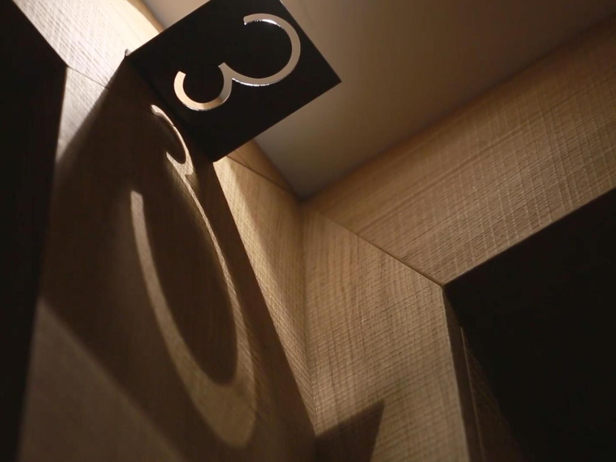A corner of a room with a geometric wall design and a hanging sign with a number.