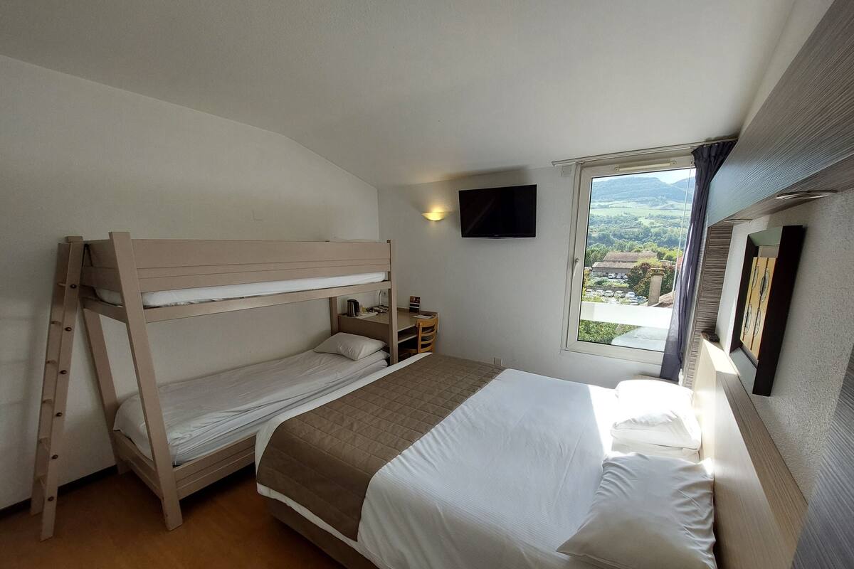 Un dormitorio con literas, un escritorio, una silla, un televisor y una ventana con vistas.